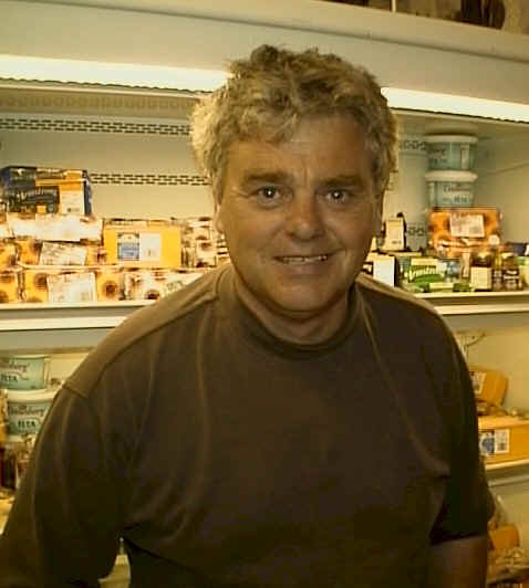 Colin, one of the store's owners, stands in front of the well-stocked deli case.