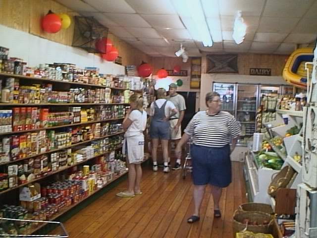 Customers browse a good selection of fresh produce, groceries, and supplies.